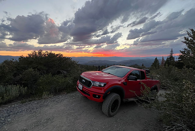Red Truck parked outside near trees with sunset in background | Quality Automotive Servicing