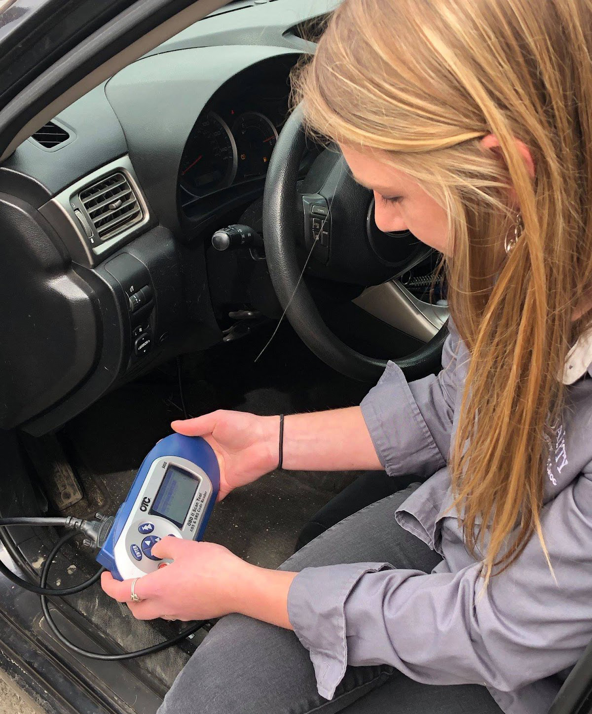 Woman with device in car | Quality Automotive Servicing